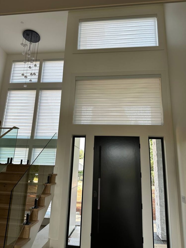 Window shades fitted to the tall windows above a modern entry door