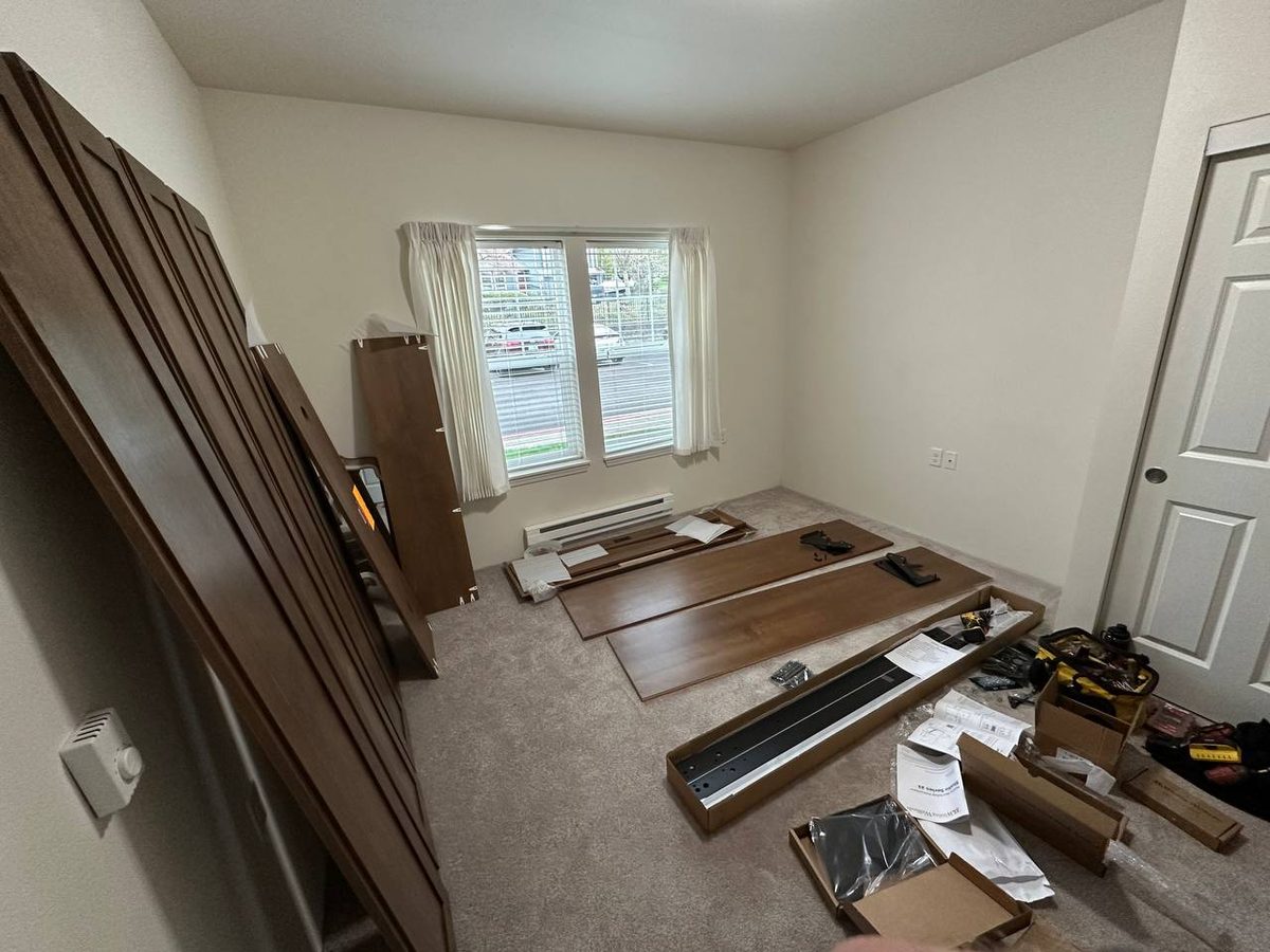 Murphy bed cabinet panels and hardware laid out on a guest room floor