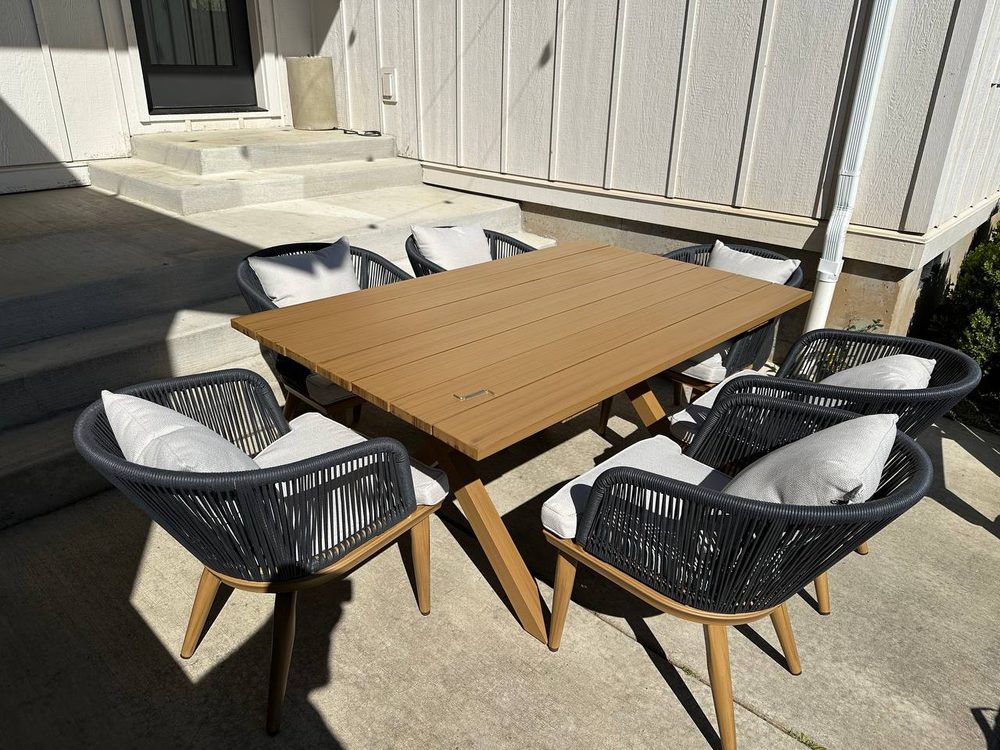 Outdoor dining table and six chairs assembled and set on a patio