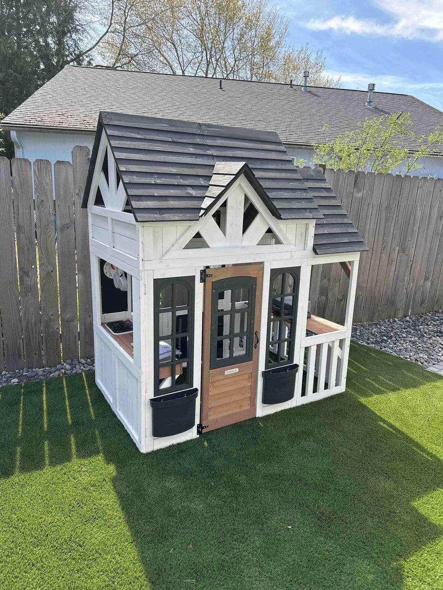 Finished white and black kids playhouse standing in the backyard
