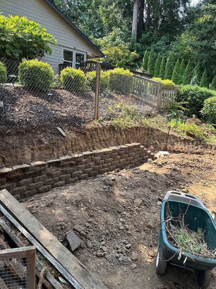 Block retaining wall rebuilt along a sloped yard with debris cleared out