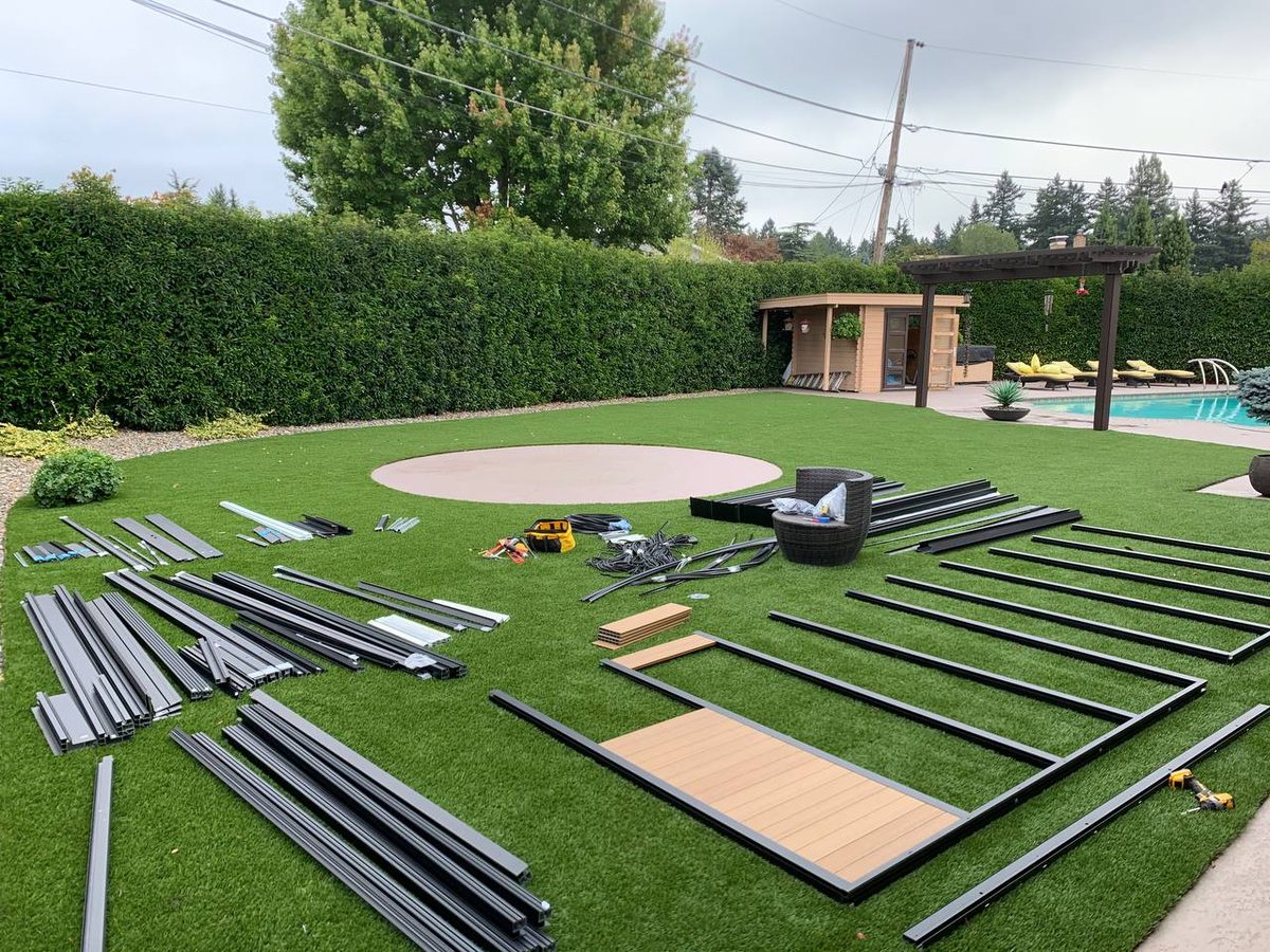 Modular studio frame rails and panels laid out across a backyard lawn