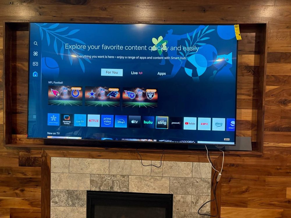 Television mounted above a stone fireplace on a wood accent wall