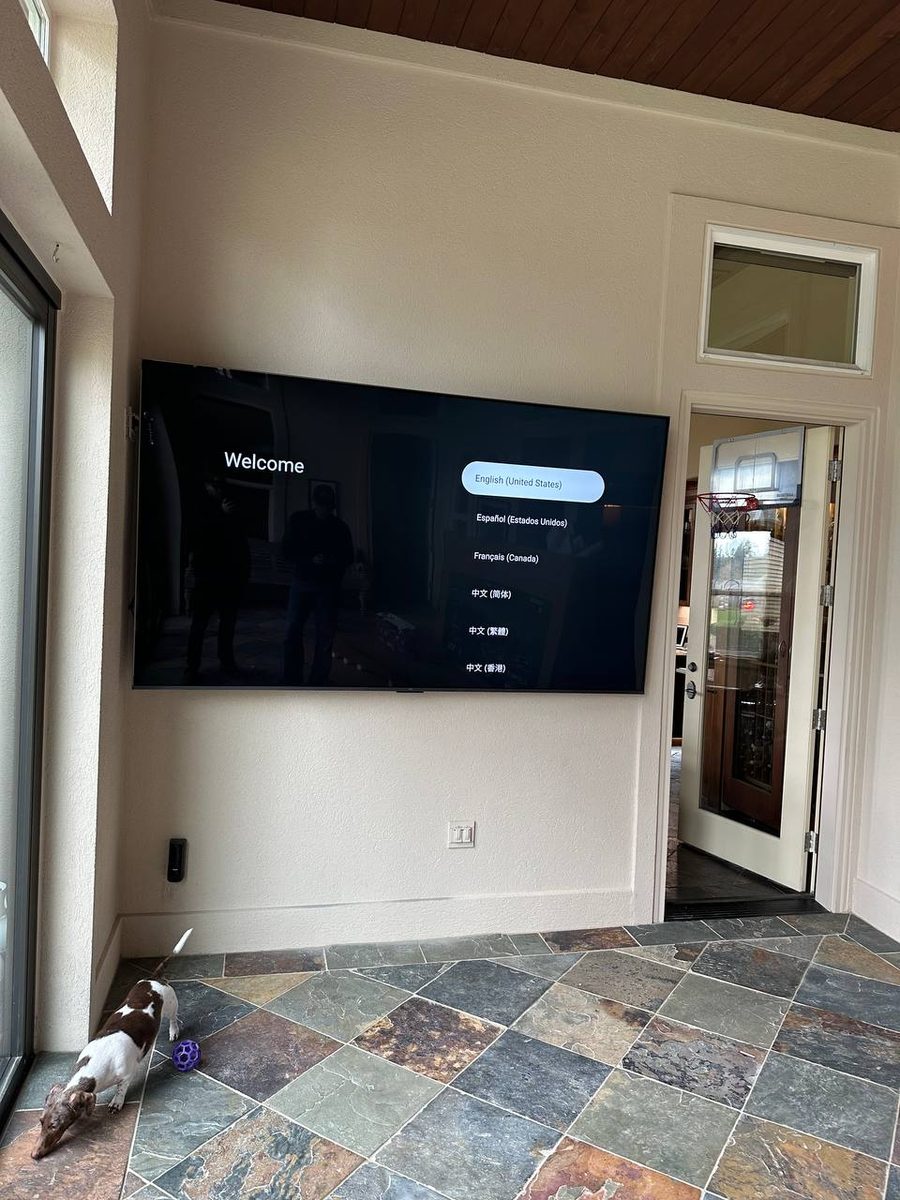 TV mounted level on the wall with cables hidden and speakers set alongside